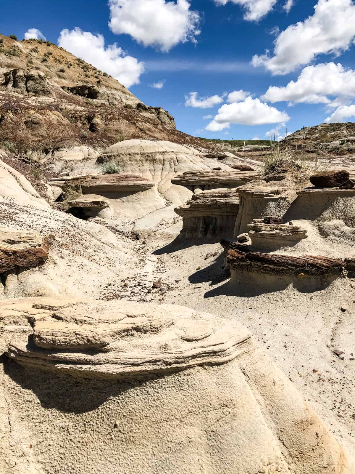 hoodoos on the Dinosaur Trail set against a blue sky and white clouds
