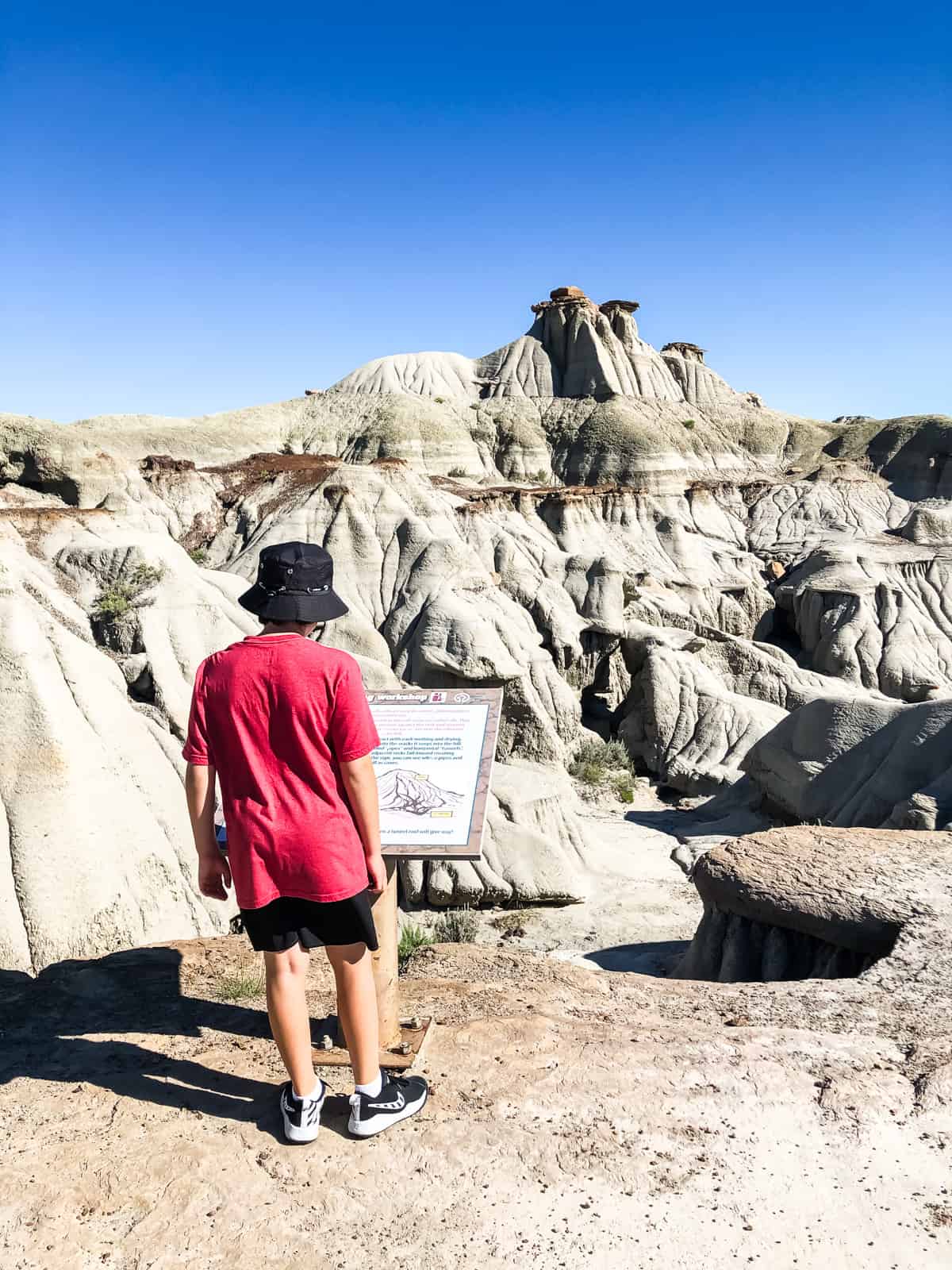 A little boy reading an interpretive sign on a walk through the hoodoos