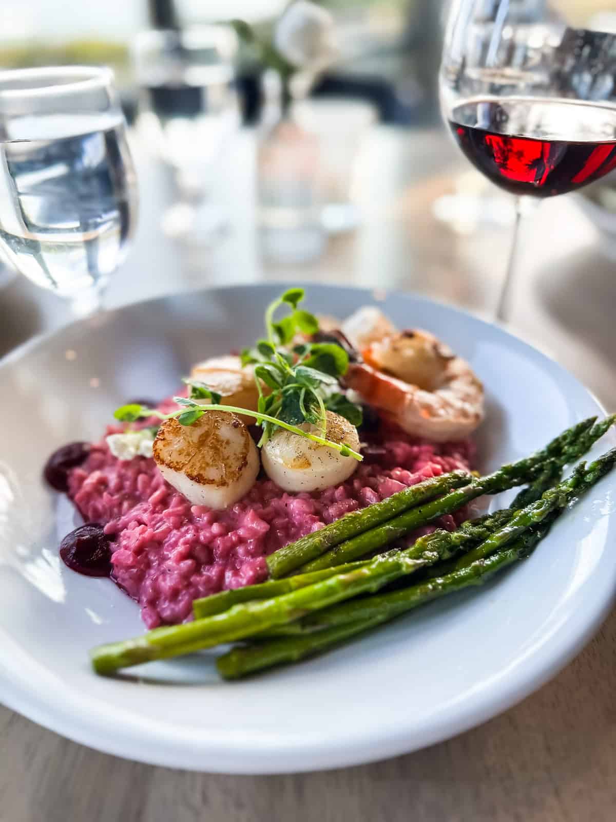 a plate of scallops on beet risotto